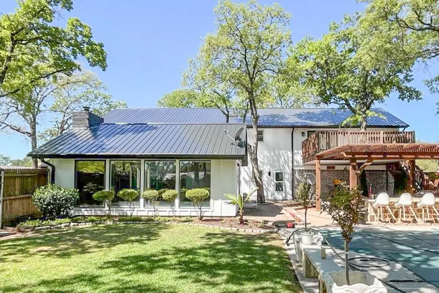 Modern home with standing seam metal roof, backyard view with green trees