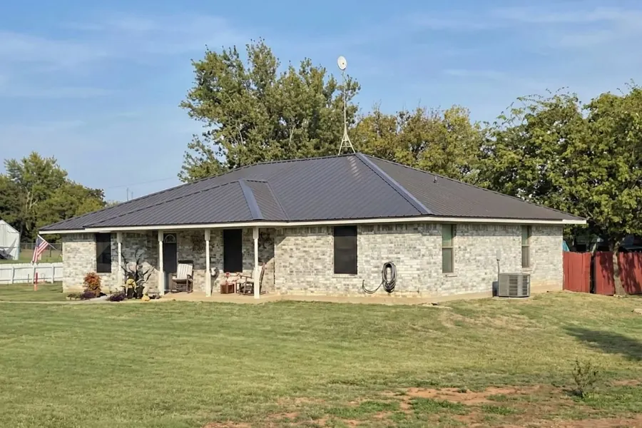 Stone ranch home with metal roof and American flag