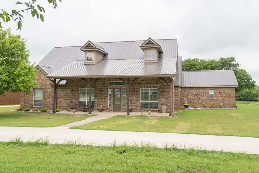 Texas brick and stone home with dark metal roof and dormers