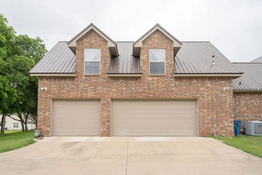 Two-story brick home with metal roof and dual dormers
